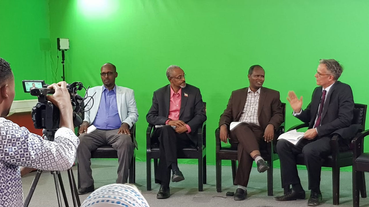 Journalism faculty members sitting in front of cameras in a green screen studio room