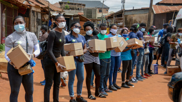 A line of women wearing masks and holding shipments