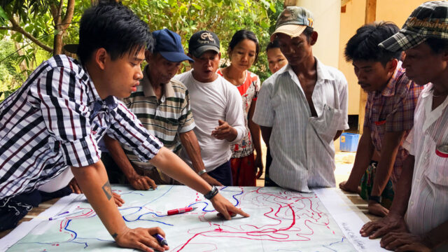 A team of people gathered around a map discussing a plan