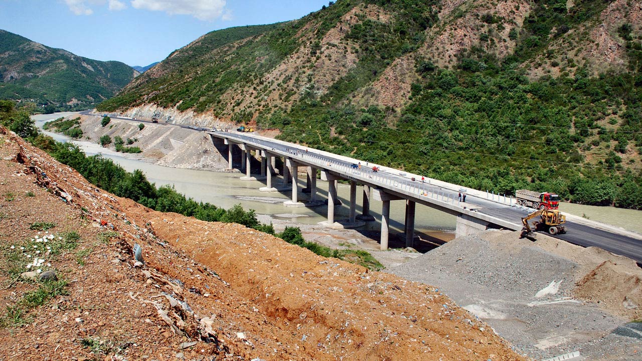 Wide view of the repaving of a highway bridge passing over a river through a valley