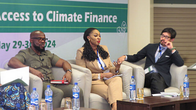 Forum speakers seated in a row of armchairs under a banner that reads “Roundtable on State Access to Climate Finance”