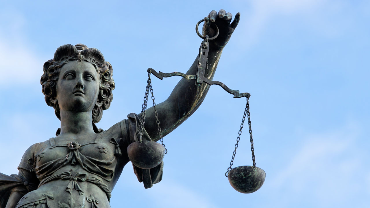 Lady Justice statue holding up her weighing scale against the sky