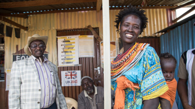 Rural community members smiling in front of a local UK Aid centre