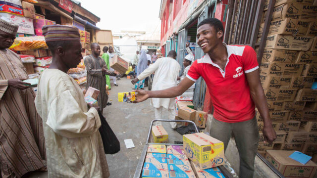Street vendor selling a boxed trinket to shoppers