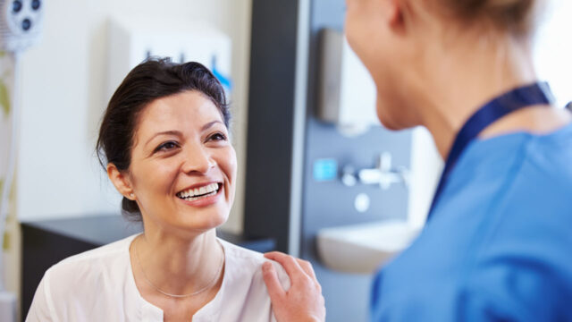 A doctor conversing with a patient, hand on shoulder