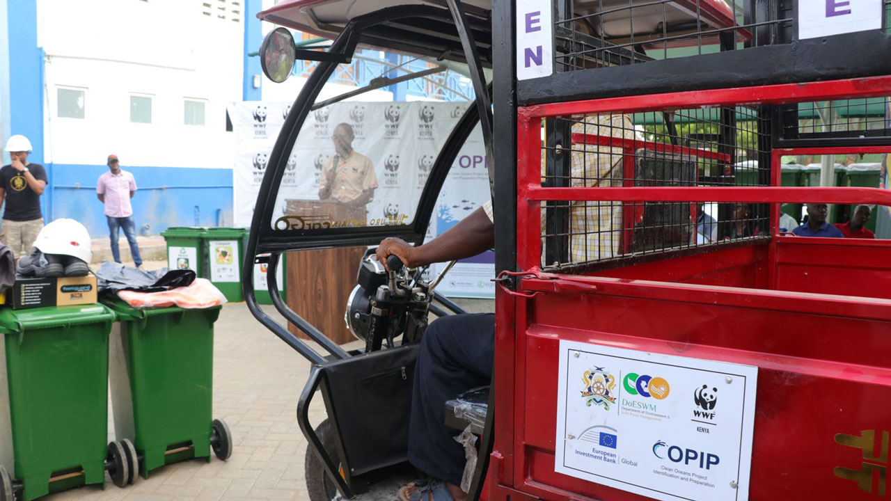 A red waste collection tuk-tuk vehicle at a COPIP event