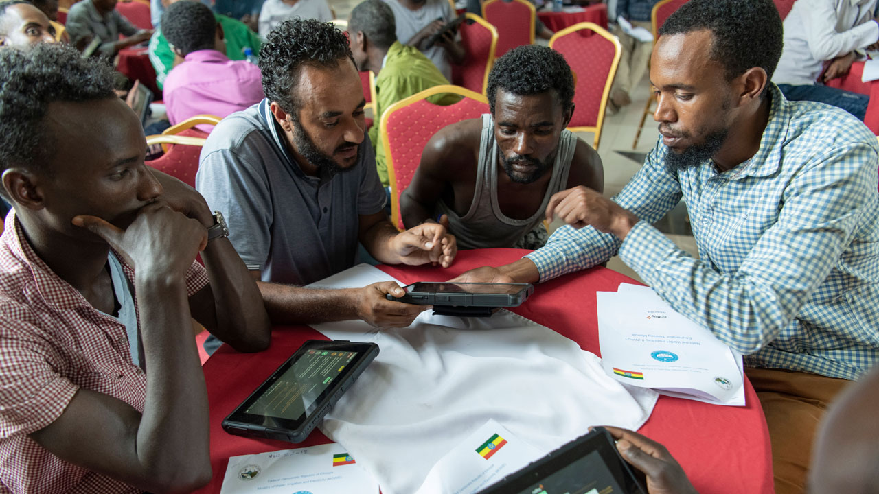 Four people gathered at a table reviewing data on a phone together