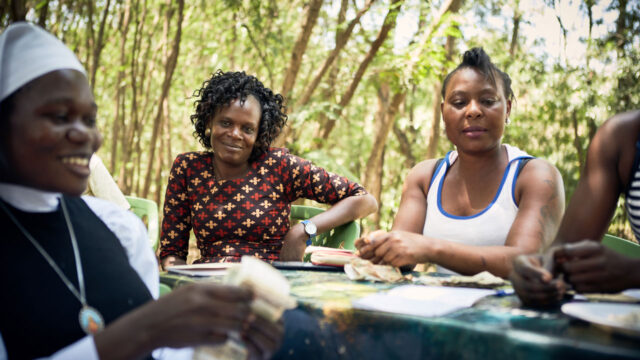 Three women at an event table outdoors, one of them sorting money
