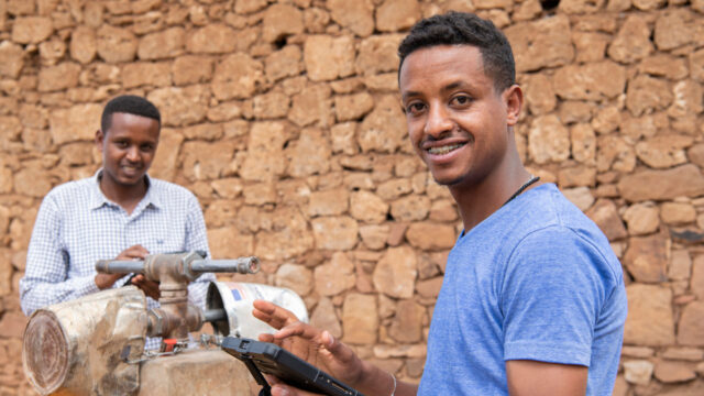 Two field scientists with tablets at a standpipe