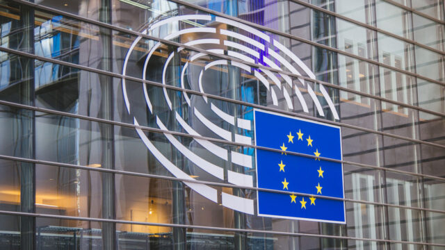 Close angled view of a European Union flag logo on the glass front facade of a modern building