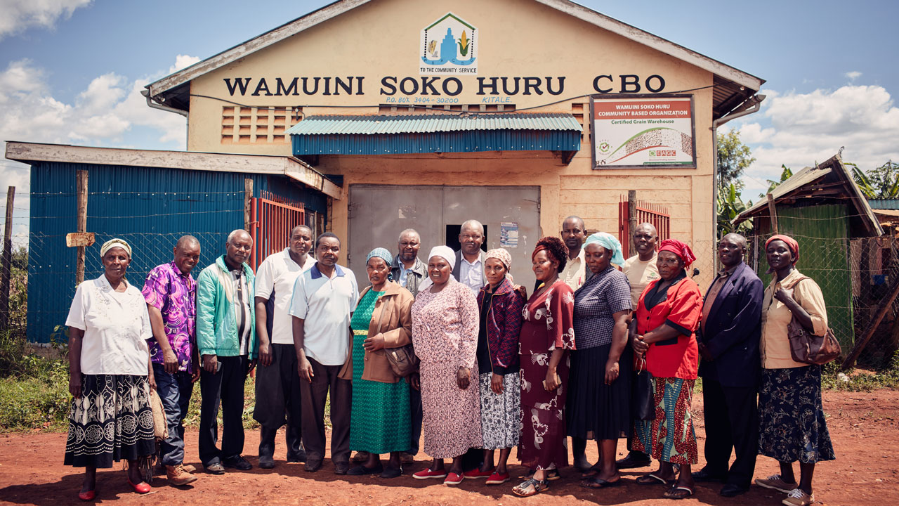A group of Kenyan agricultural workers in front of the Wamuini Soko Huru CBO grain warehouse