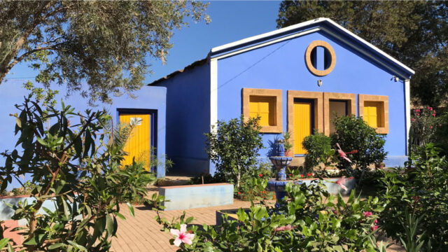 Exterior of a blue Dar Talib/as student boarding house with yellow doors windows