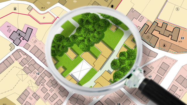 A magnifying glass highlights a green park area on a detailed urban map with buildings and streets