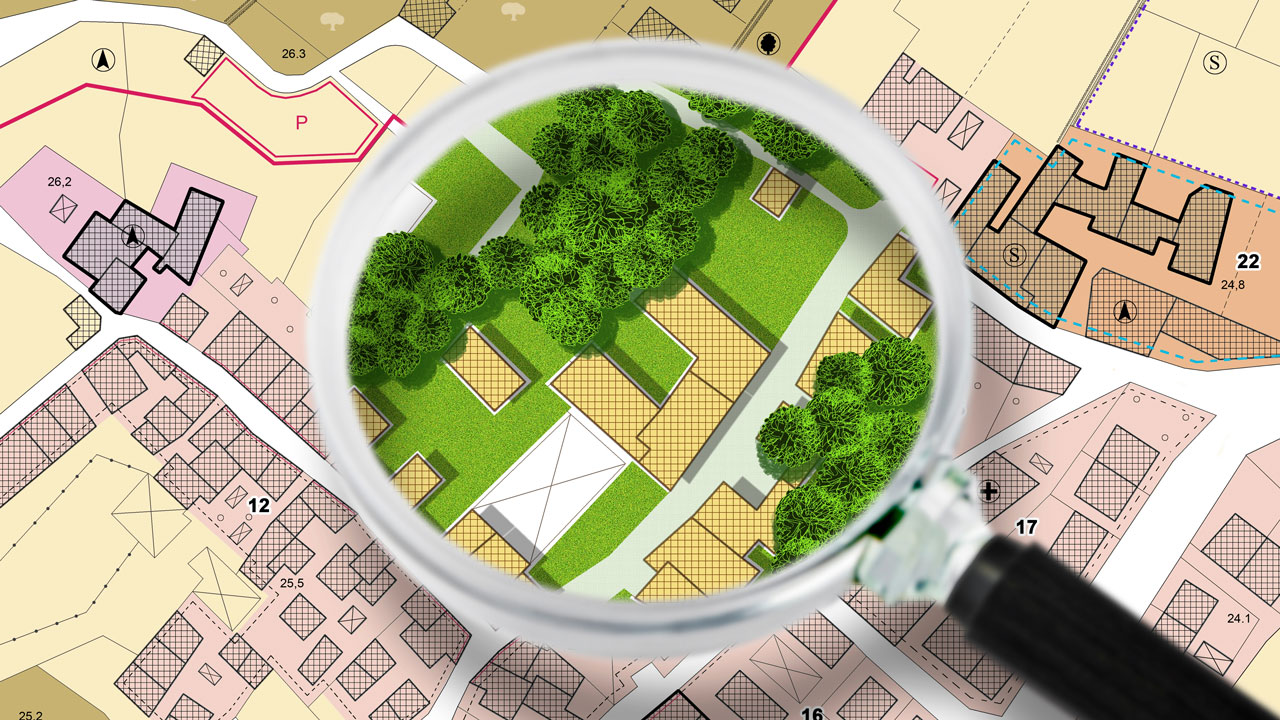 A magnifying glass highlights a green park area on a detailed urban map with buildings and streets
