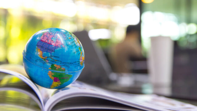 A miniature globe with an out-of-focus conference table in the background