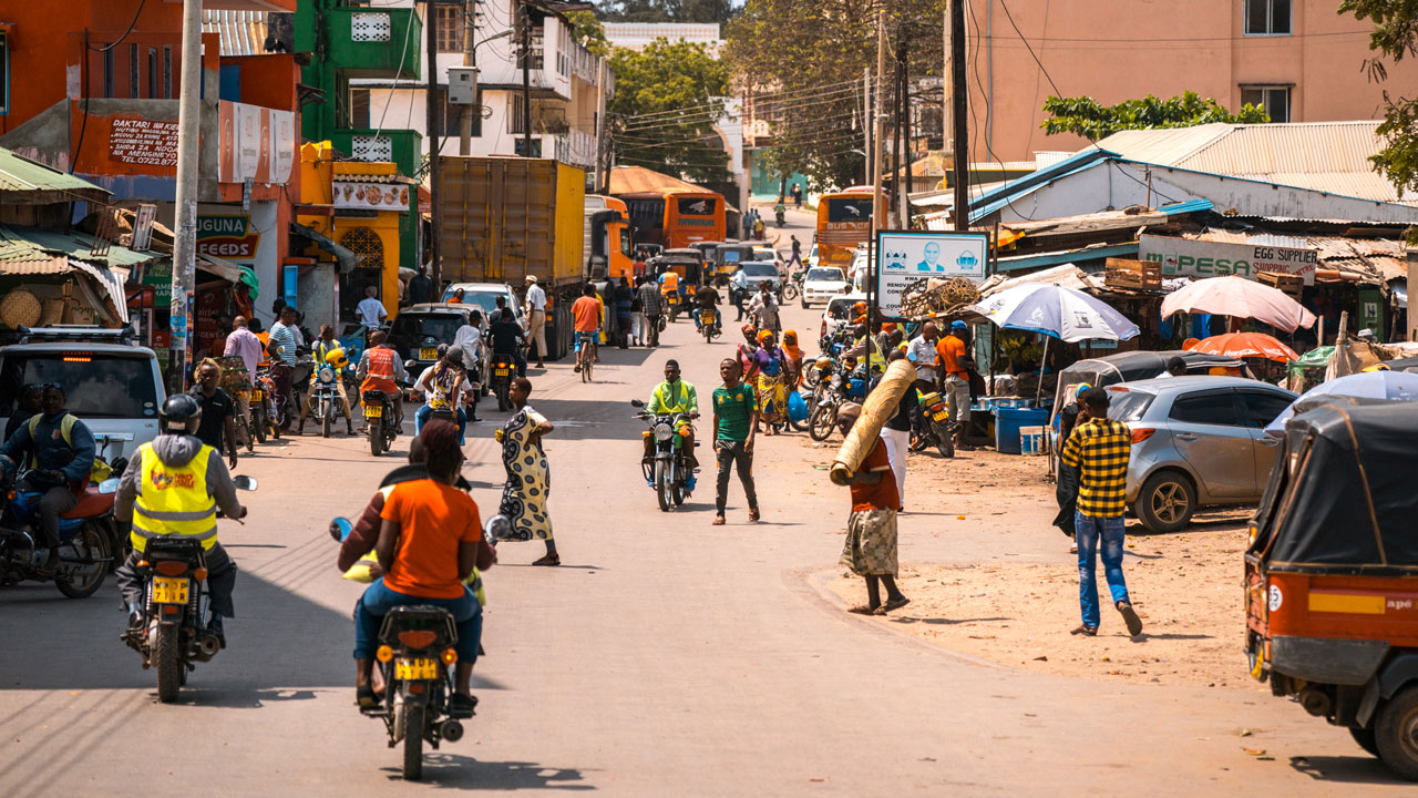 The bustling street of a town with pedestrians and motorcyclists
