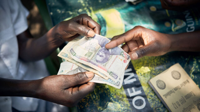 Hands of two people exchanging Kenyan shilling notes