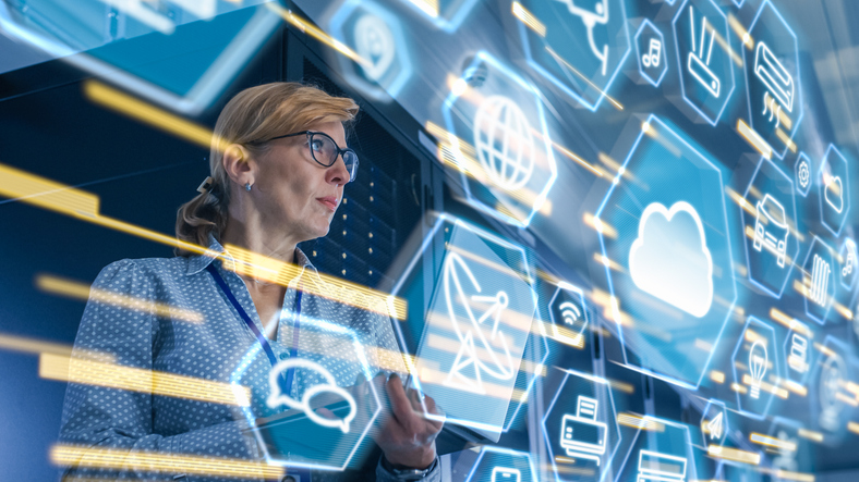Female IT server specialist standing in data centre with interface icons in the foreground.